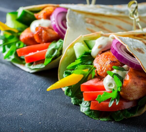 Closeup of grilled tortilla with chicken, tomatoes and lettuce