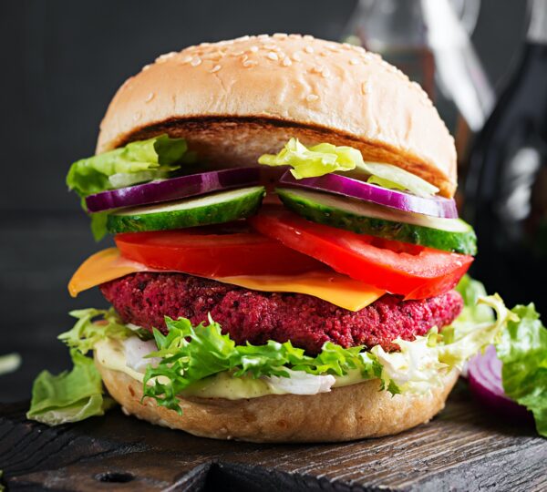 Healthy vegan beetroot burgers with tomato, cucumber, red onion and sauce.